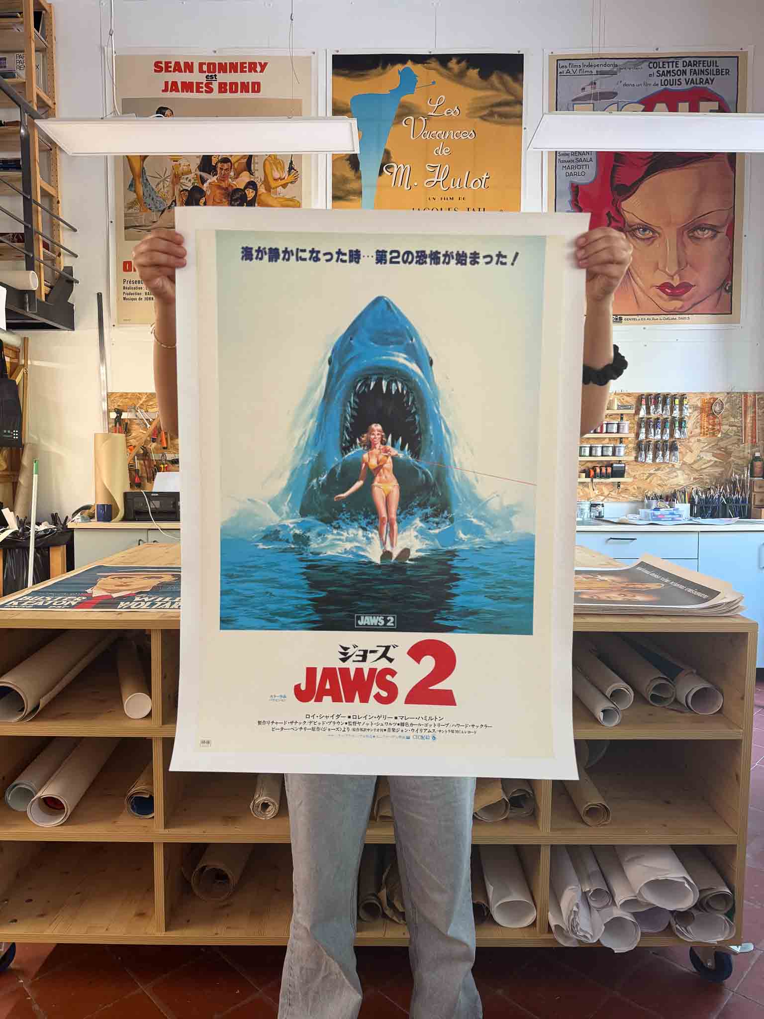 Affiche japonaise du film Jaws 2 avec un requin surgissant derrière une skieuse nautique, typographie rouge et bleue