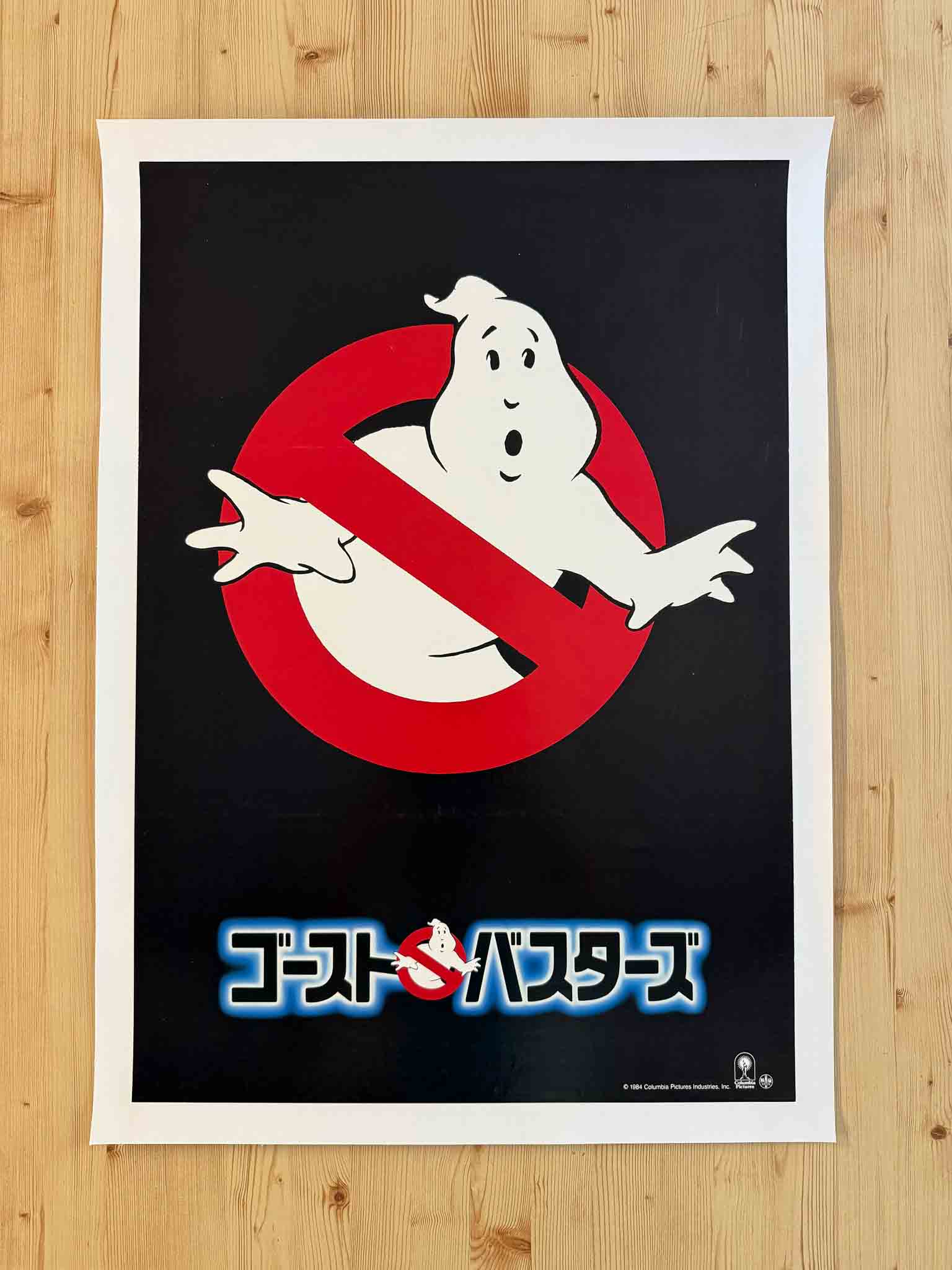 Affiche teaser japonaise du film Ghostbusters avec le logo du fantôme barré et le titre en japonais sur fond noir